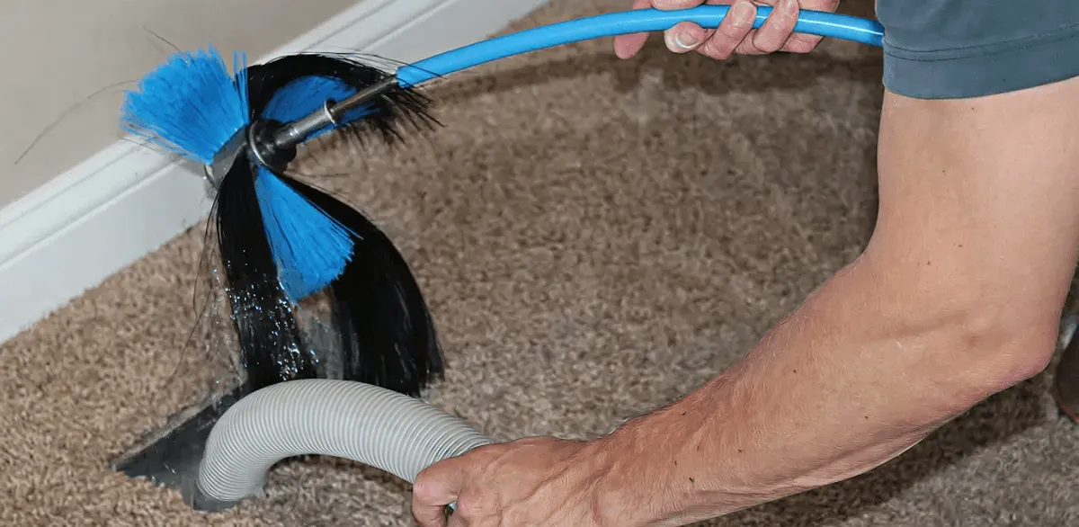 Dryer vent cleaning technician brushing lint from a vent line in Fargo, ND